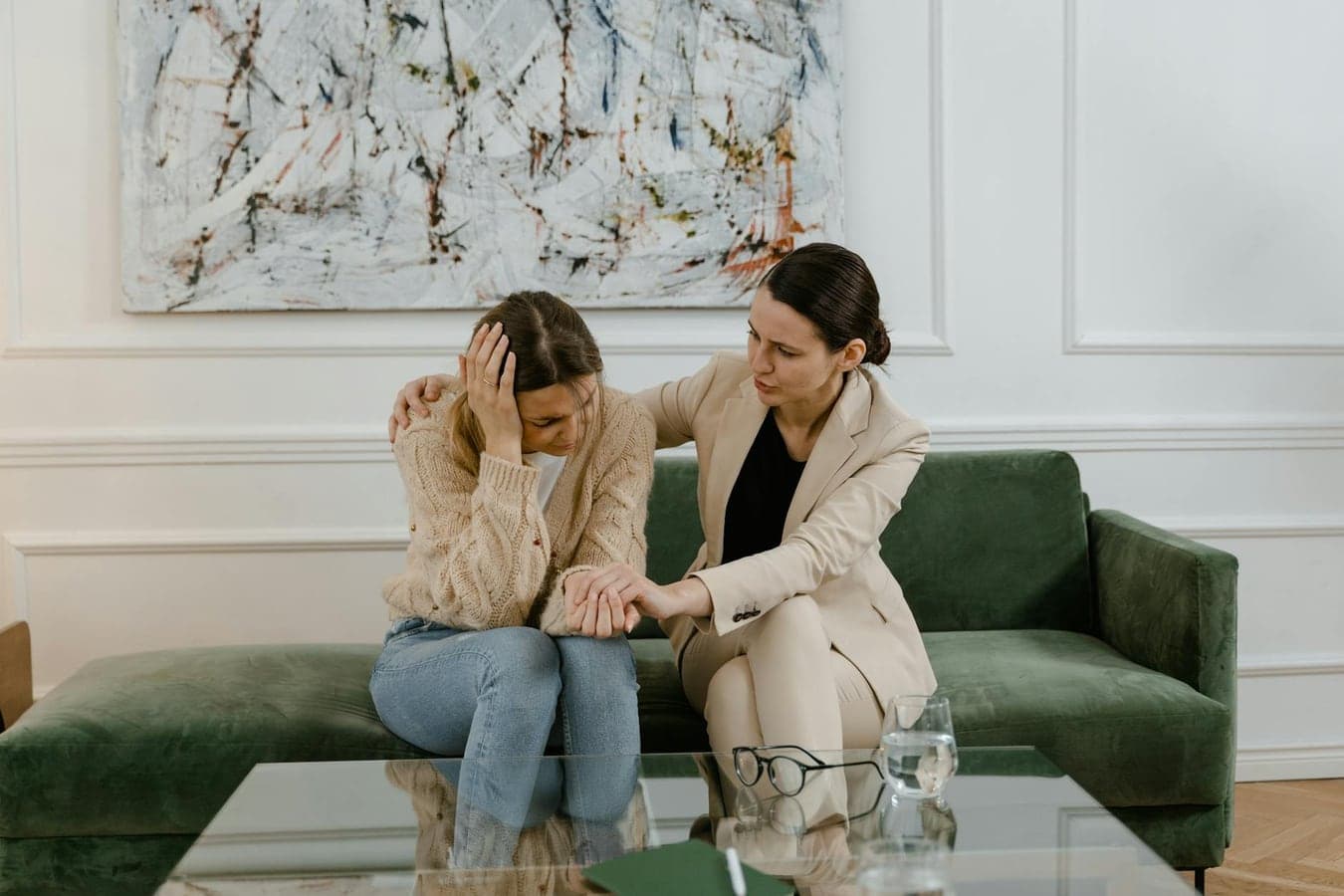 A therapy session where a concerned therapist supports a distressed woman in a modern office.